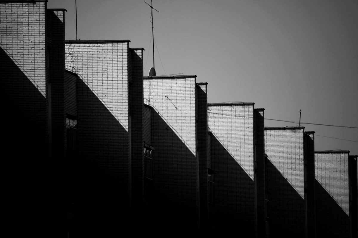 Una línea diagonal de luz que sube en tramos horizontales y verticales sobre fachadas escalonadas, nunca en diagonal directa: la firma visual de un step chart, que mantiene el valor constante hasta el instante exacto del cambio